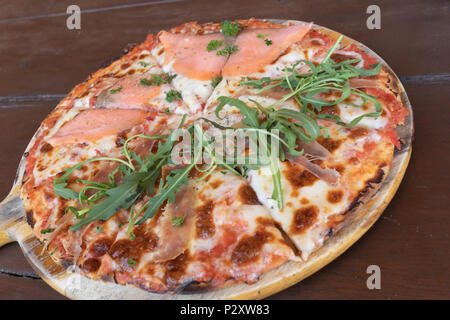 Délicieux Saumon au four pizza italienne du four pour le déjeuner ou le dîner se situent sur le plateau de bois sur la table en bois Banque D'Images