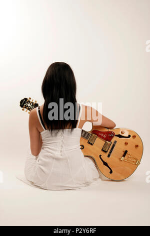 Jeune femme tenant une guitare électrique acoustique Banque D'Images