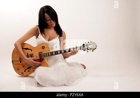 Jeune femme jouant une guitare électrique acoustique semi Banque D'Images