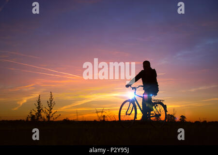 Homme monter sur le vélo. Rider sur vélo rétro silhouette ciel coucher de soleil avec en arrière-plan. Des loisirs sains et l'activité. Banque D'Images