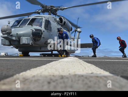 Océan Pacifique (9 août 2016) marins affectés à la classe Arleigh Burke destroyer lance-missiles USS Shoup (DDG 86) exécuter pour enlever des cales et des chaînes d'un MH-60S Sea Hawk affecté à l'agicians «' de l'Escadron d'hélicoptères grève maritime (HSM) 35 sur le pont d'envol du navire. Shoup est actuellement en cours d'exerecises de routine. (U.S. Photo par marine Spécialiste de la communication de masse 2e classe Siobhana R. McEwen/libérés) Banque D'Images