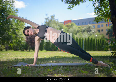 Belle fille sportive engagés dans la gymnastique yoga dans le parc. Banque D'Images