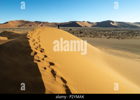 Des empreintes de pas dans les lignes de crête ondulée de couleur orange et rouge de dunes, Sossusvlie Hidden Vlei Namibie Banque D'Images