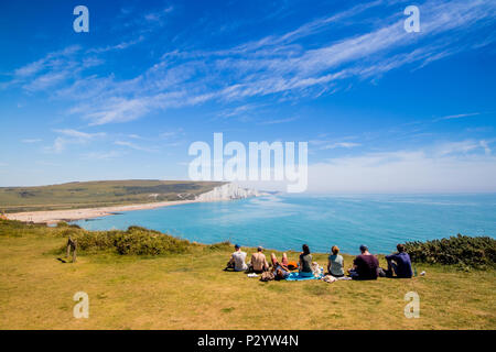 Les promeneurs assis au bord de la falaise en direction de Cuckmere Haven, sept Sœurs Country Park près de Eastbourne, East Sussex, UK Banque D'Images