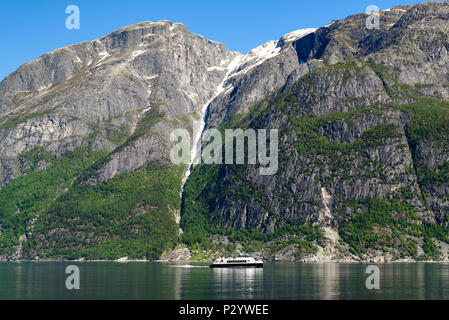 Petit tour en bateau ou en ferry dans un fjord sur une journée ensoleillée. Des pics de montagne de neige et de glace à l'arrière-plan. Location Eidfjord en Hordaland, Norvège. Banque D'Images