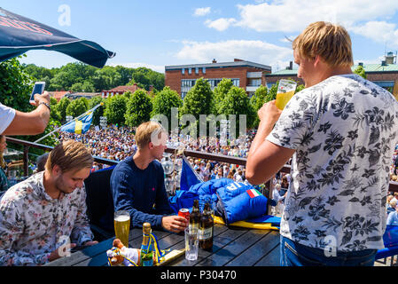 Ronneby, Suède - 15 juin 2018 : Voyage documentaire de la vie quotidienne et le lieu. Les jeunes hommes ayant une bière à un balcon au-dessus du carré à la recherche à la c Banque D'Images