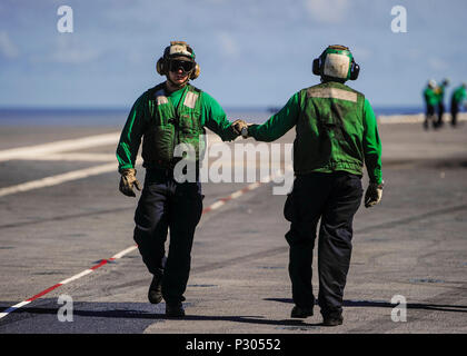 160816-N-VH385-396 OCÉAN ATLANTIQUE (16 août 2000 16, 2016) une paire de Boatswain's aviation mates (équipement) bump fists qui traversent le pont d'envol du porte-avions USS George Washington (CVN 73) pendant les opérations de vol. George Washington, homeported à Norfolk, est en cours la réalisation des qualifications de l'opérateur dans l'océan Atlantique. (U.S. Photo par marine Spécialiste de la communication de masse 3 Classe Wyatt L. Anthony) Banque D'Images