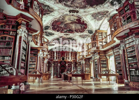 Le 18e siècle Bibliothèque de l'abbaye de Saint Gall à Saint-Gall, Suisse, attire les visiteurs tant pour son intérieur de style rococo somptueux que pour sa collection de littérature médiévale. Considéré comme la plus ancienne et la plus riche bibliothèque Suisse, certains de ses 160 000 livres datent de la fondation de l'abbaye dans le milieu du viiie siècle. Les livres les plus rares sont conservés dans des caisses en bois à façade en verre sous les plafonds de style baroque avec des peintures. L'abbaye est maintenant un site du patrimoine mondial de l'UNESCO et sa remarquable bibliothèque est ouverte au public. Banque D'Images