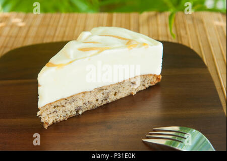 Tranche de gâteau avec de la crème glacée Crème glacée à la vanille sur pain de banane avec un tourbillon de caramel sur une plaque de bois Banque D'Images