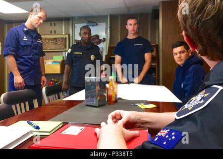 Le lieutenant Cmdr. William Adams, commandant de la WLB-215 USCGC (Sequoia), Jim Kloulechad Palau, Police nationale, Ensign Luc Trautwein et le lieutenant J.G. Charlie Trotten, officier des opérations, écouter une liste des récentes violations observées par le personnel de l'Agence de gestion des pêches de l'Australie au cours de l'arraisonnement en haute mer donnée par Lydia Woodhouse shiprider à bord de l'AFMA un Sequoia pendant qu'ils sont en cours dans l'océan Pacifique le 30 août 2016. Les partenaires de la Garde côtière des États-Unis avec l'AFMA d'élargir sa compétence et les autorités à mener des inspections à la zone de la haute mer Banque D'Images