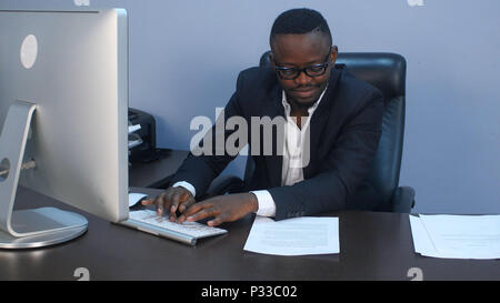 Portrait de jeunes afro-american businessman sérieux travail avec ordinateur portable et le document Banque D'Images