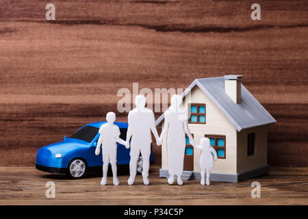 Figures humaines debout devant de la maison et de la voiture bleue sur planche en bois Banque D'Images