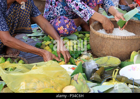 La préparation de la nourriture pour un mariage, l'emballage et la gourmandise du riz dans des feuilles de bananier, pour la cuisson sur feux ouverts à l'extérieur. Banque D'Images