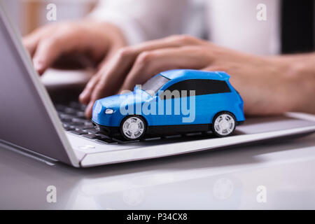 Close-up d'une petite voiture bleue sur le clavier de l'ordinateur portable Banque D'Images