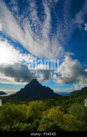 Sommet de montagne dans les collines couvertes de jungle de Moorea avec un fond de nuages spectaculaires contre un ciel bleu. Banque D'Images