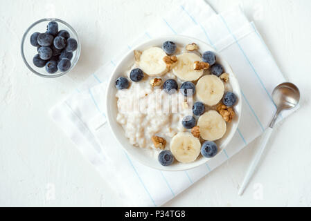 Bouillie d'avoine avec des noix, des bleuets et de la banane dans un bol - petit déjeuner bio en bonne santé, de l'avoine avec des fruits, miel et noix Banque D'Images