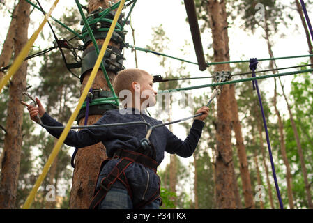 Activité zip line. Petit garçon heureux profiter de randonnées au parc aventure. Banque D'Images