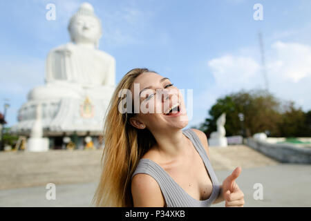 Young woman showing Thumbs up, statue du Bouddha blanc à Phuket en arrière-plan. Banque D'Images