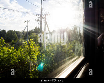 Vue de la fenêtre d'un train, en partie floue, lors d'une journée ensoleillée. Banque D'Images