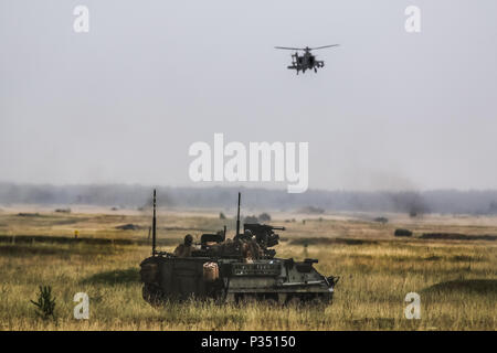 Un véhicule blindé intérimaire 'Stryker" et un hélicoptère Apache AH-64 avec 1er Escadron, 2e régiment de cavalerie, tenter de se doter d'une région au cours d'un exercice multinational de formation pour Puma 2 Groupe de combat avec la Pologne à Bemowo Piskie Domaine de formation, la Pologne le 14 juin 2018 dans le cadre de la grève 18 Sabre. L'exercice de cette année, qui se déroulera du 3 au 15 juin, des tests des alliés et des partenaires de 19 pays sur la capacité de travailler ensemble pour prévenir les agressions dans la région et d'améliorer la capacité de chaque unité d'effectuer leur mission. (U.S. Photo de l'armée par la CPS. Hubert D. Delany III /Mobile d'affaires publiques 22 Banque D'Images