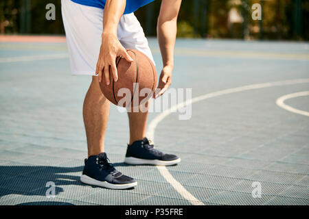 Les jeunes mâles d'Asie de basket-ball dribble et pratique de maniement du ballon habileté sur cour. Banque D'Images