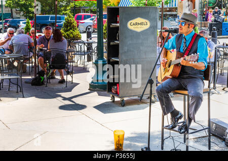 ASHEVILLE, NC, USA-10 le 18 juin : un artiste de rue chante et joue de la guitare, tandis que les clients à dîner à l'extérieur du Carmel Cuisine et Bar. Banque D'Images