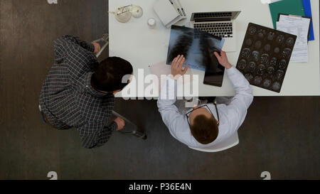 Médecin homme discutant avec rx rachis male patient sur des béquilles Banque D'Images
