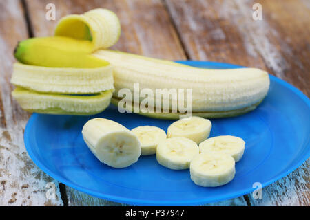 Tranches de banane fraîche et une banane entière dans la région de Peel sur plaque bleue Banque D'Images