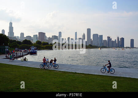 Les visiteurs de Chicago ride vélos partagent le long du lac sur le Museum Campus avec la ville en arrière-plan. Banque D'Images