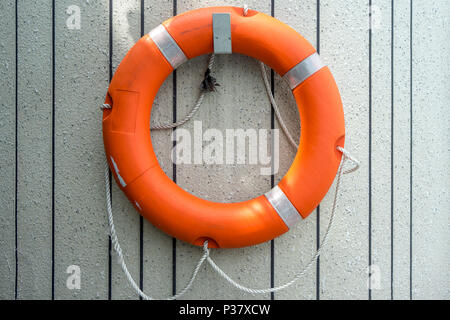 Bouée Orange pierre accroché sur mur de ciment, l'eau l'équipement d'urgence sauvetage Banque D'Images