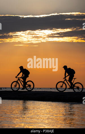 Deux hommes en silhouette ride vtt sur la côte Adriatique, près de la ville de Piran en Slovénie. Banque D'Images