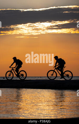 Deux hommes en silhouette ride vtt sur la côte Adriatique, près de la ville de Piran en Slovénie. Banque D'Images