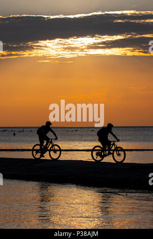 Deux hommes en silhouette ride vtt sur la côte Adriatique, près de la ville de Piran en Slovénie. Banque D'Images