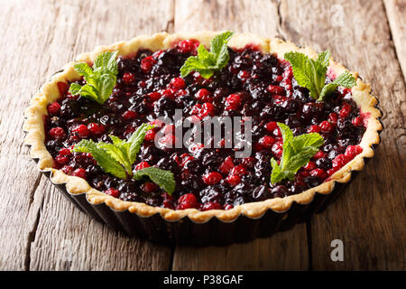 Très belle tarte sucrée avec des baies de cassis, de bleuets et de canneberges close-up dans un plat allant au four, sur une table horizontale. Banque D'Images