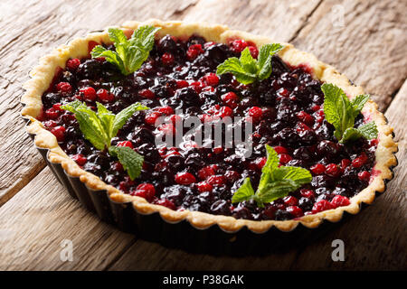 Tarte rustique aux baies de cassis juteux, les bleuets et les canneberges close-up dans un plat allant au four, sur une table horizontale. Banque D'Images