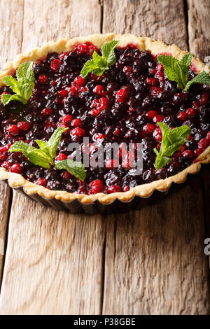 Tarte aux baies de cassis délicieux, canneberges et bleuets est décoré de menthe poivrée close-up dans un plat allant au four, sur la table verticale. Banque D'Images