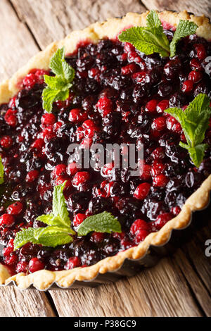 Tarte d'été avec des baies de cassis, canneberges et bleuets est décoré à la menthe close-up sur la table verticale. Banque D'Images