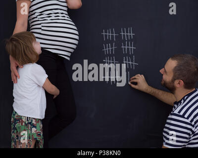 Deux jeunes femmes enceintes avec mignon comptes fille semaine de grossesse et en les écrivant à la craie sur tableau noir Banque D'Images