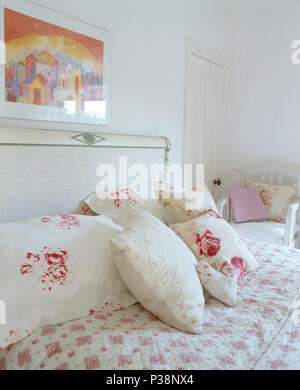 Close-up de coussins à motifs de roses , et couette sur lit laqué blanc en pays blanc chambre Banque D'Images