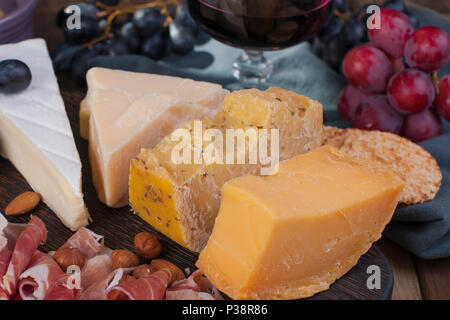 Un verre de vin rouge et un en-cas. Différents fromages italiens et prosciutto, amuse-gueules pour une partie et le vin rouge. Copy space Banque D'Images