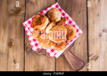 Des beignets sucrés sont frites. Des plats faits maison. Serviette dans la cage rouge. Fond de bois. L'espace de copie. télévision lay Banque D'Images