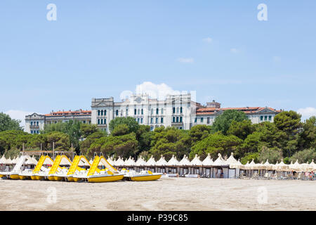 Jaune coloré de bateaux de pêche et des cabanas sur une plage privée de Lido di Venezia, Venise, Vénétie, Italie avec l'ex Grand Hôtel les Bain Banque D'Images