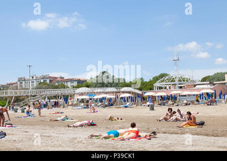 Les gens en train de bronzer sur une plage de Blue Moon, Lido di Venezia, l'île du Lido, Venise, Vénétie, Italie, sur un beau jour à la fin du printemps. Pier, des restaurants, de l'observation Banque D'Images