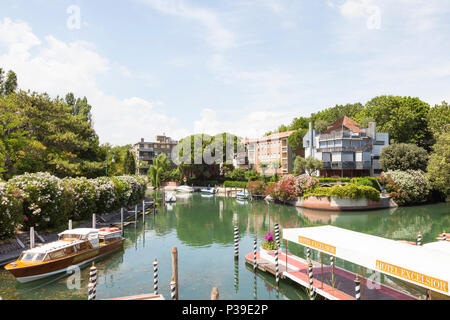 L'Hôtel Excelsior pont d'atterrissage et des bateaux sur un canal tranquille avec relfections, Lido di Venezia, l'île du Lido, Venise, Vénétie, Italie Banque D'Images