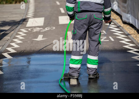 Lave-piste cyclable et trottoir en utilisant le tuyau d'eau, rues de nettoyage et de lavage de la ville. Banque D'Images