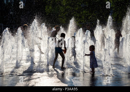 Silhouettes d'enfants courant si une fontaine dans l'été, les jardins de Piccadilly, Manchester, UK Banque D'Images