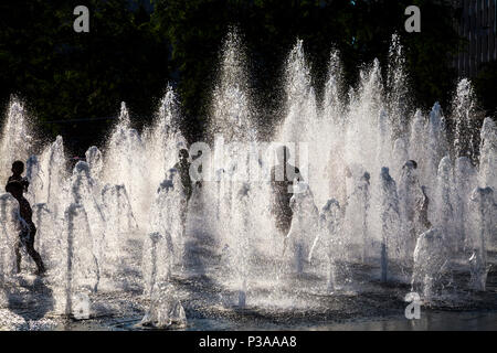 Silhouettes d'enfants courant si une fontaine dans l'été, les jardins de Piccadilly, Manchester, UK Banque D'Images