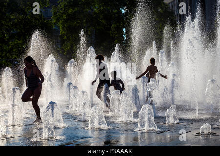 Silhouettes d'enfants courant si une fontaine dans l'été, les jardins de Piccadilly, Manchester, UK Banque D'Images