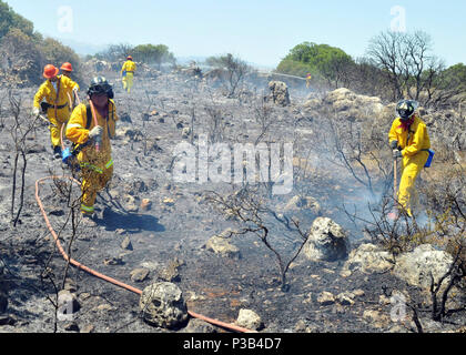 Les pompiers de la base navale américaine de la baie de Souda éteindre les restes d'un feu de brousse près du village de Pazinos dans l'ouest de la Crète, Grèce, le 11 juillet 2009. Les pompiers répondent à une demande d'aide d'organismes locaux. Banque D'Images