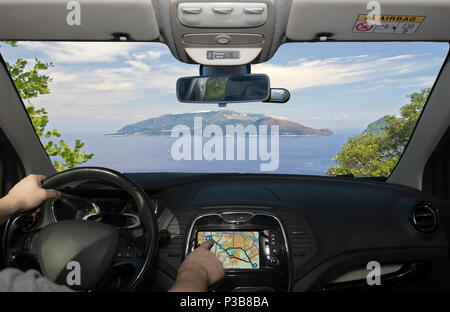 La conduite d'une voiture tout en utilisant l'écran tactile d'un système de navigation GPS vers la péninsule de Sorrento, vue de Capri, dans la baie de Naples, Italie Banque D'Images